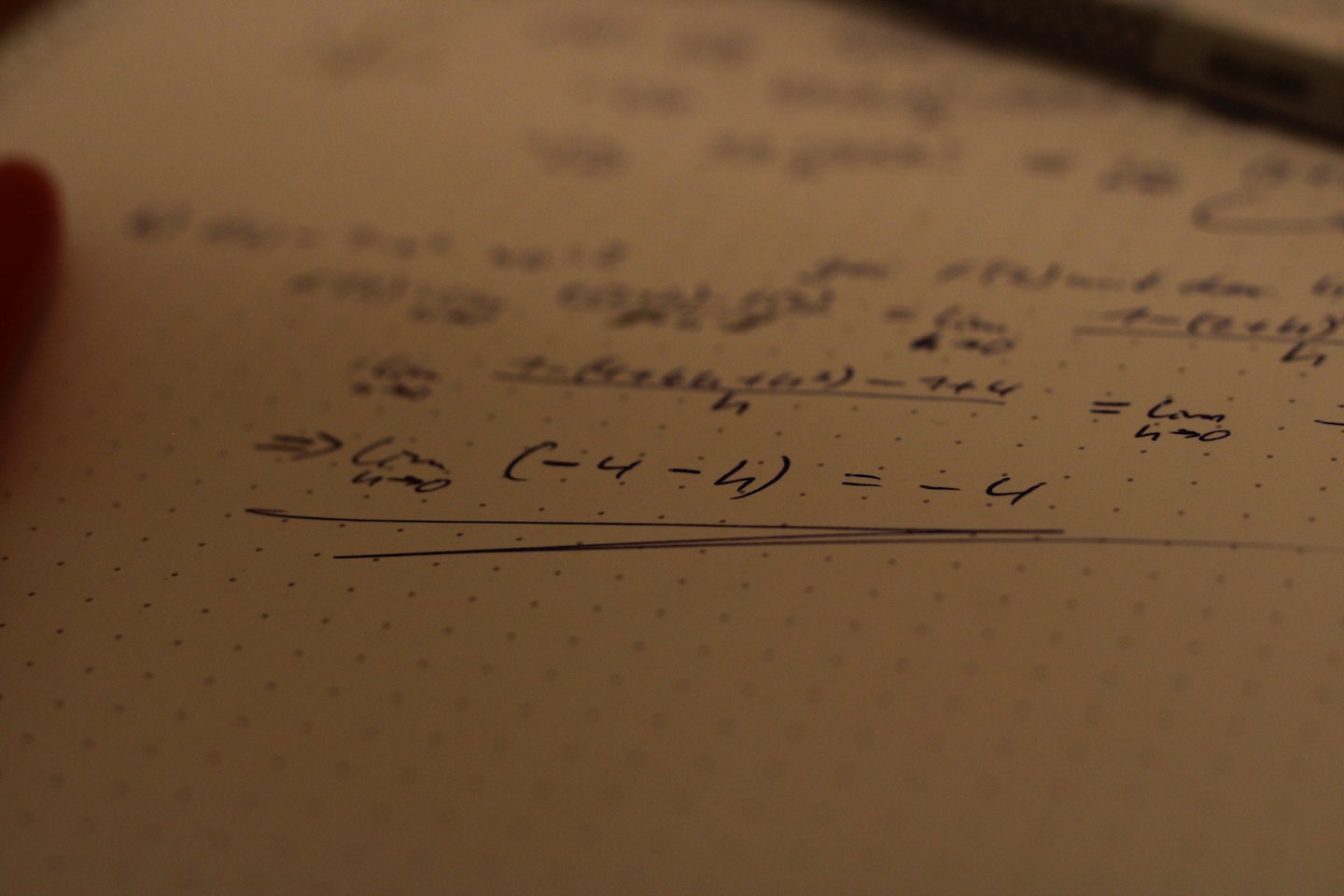 Handgeschriebene mathematische Gleichungen auf gepunktetem kariertem Papier.