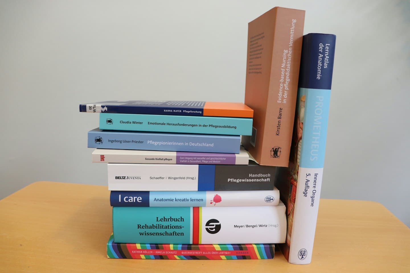 Stapel deutscher und englischer wissenschaftlicher Lehrbücher auf einem Holztisch.